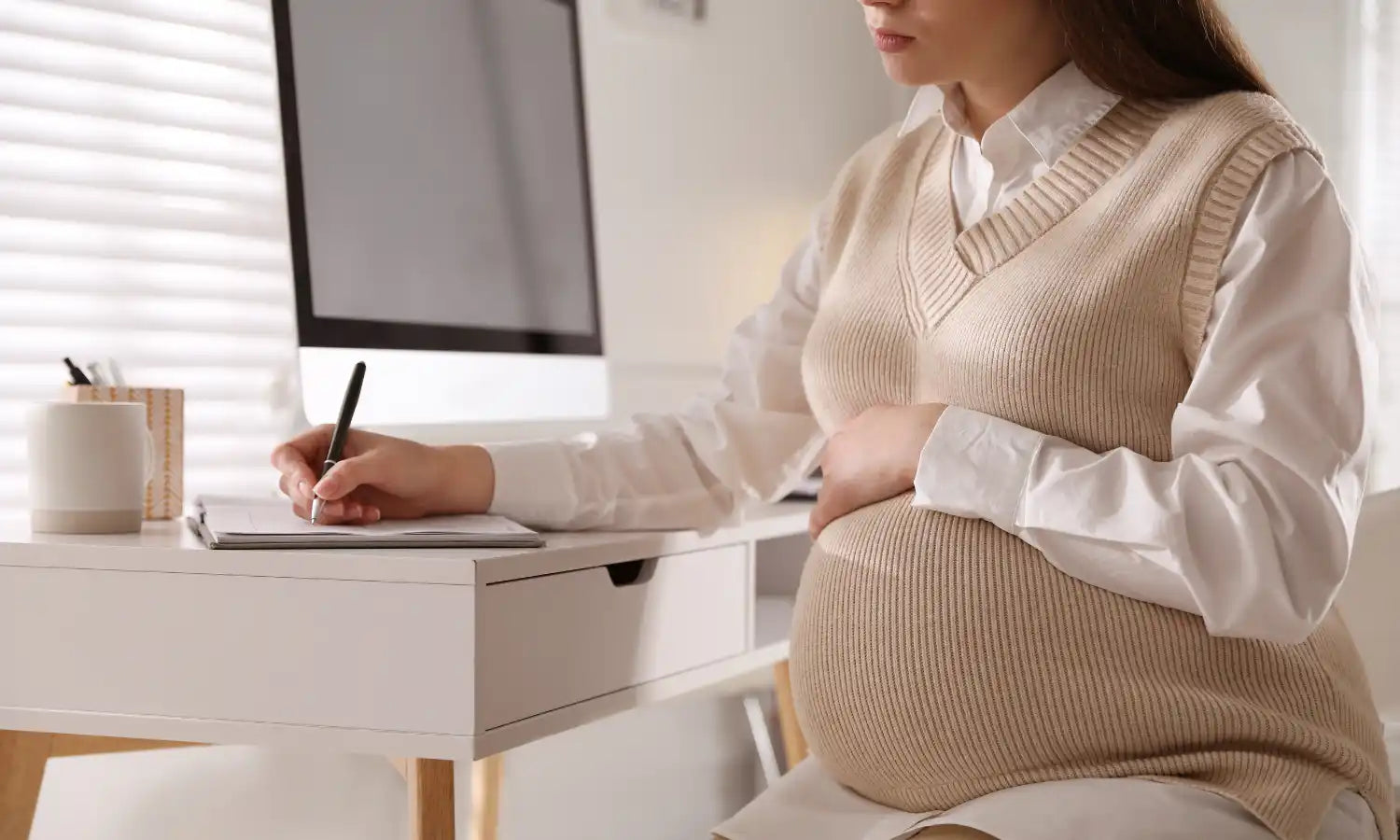 Schwangere Frau, die an einem Schreibtisch arbeitet