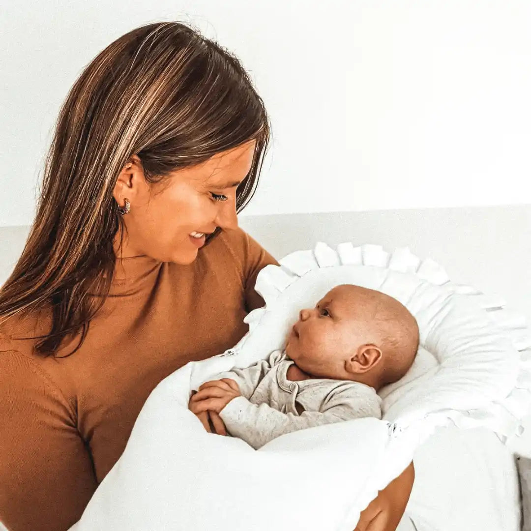 Eine Frau, die ein Baby in einer weißen Decke hält.