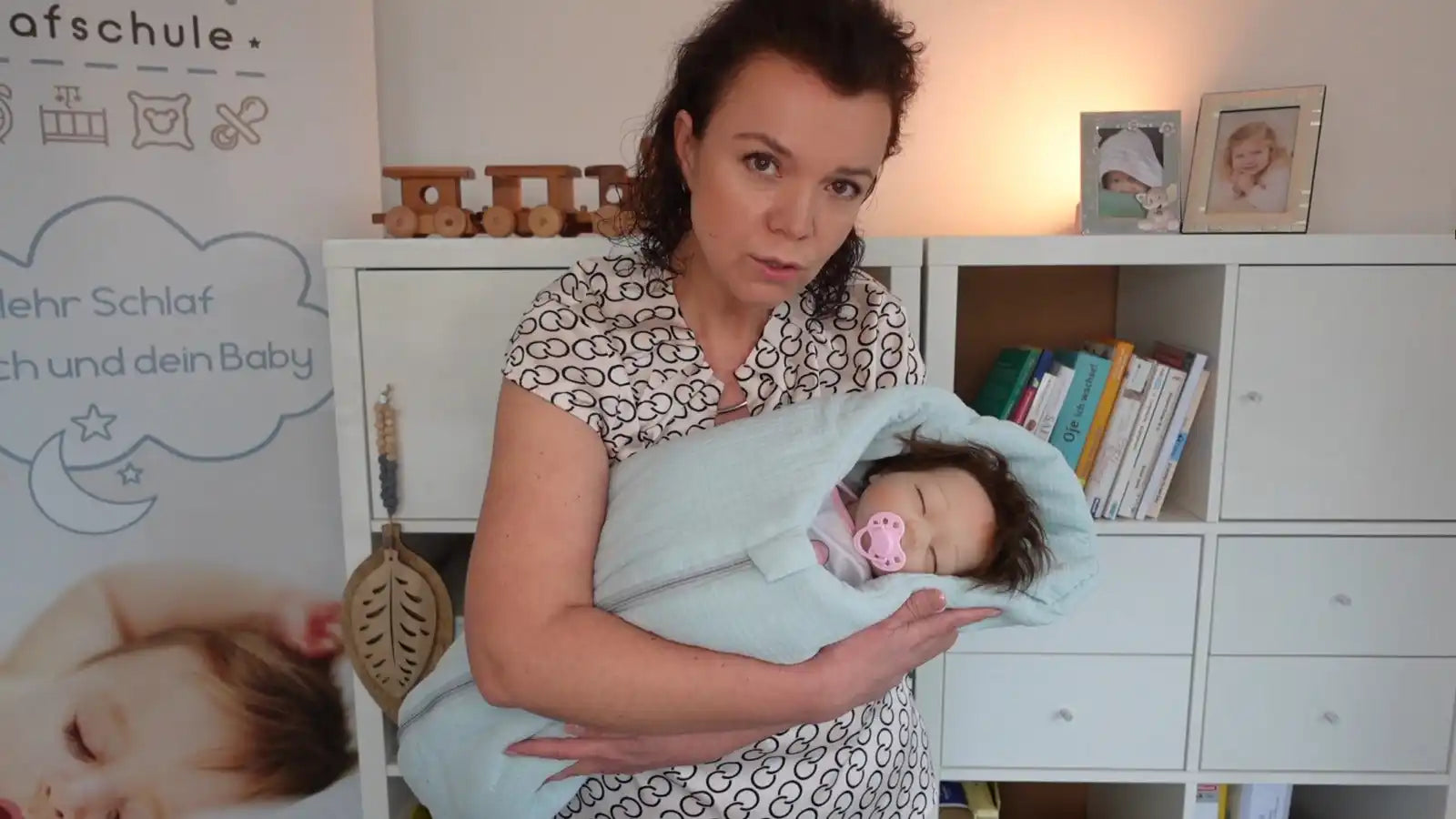 Eine Frau, die ein eingewickeltes Baby mit einem Schnuller hält.