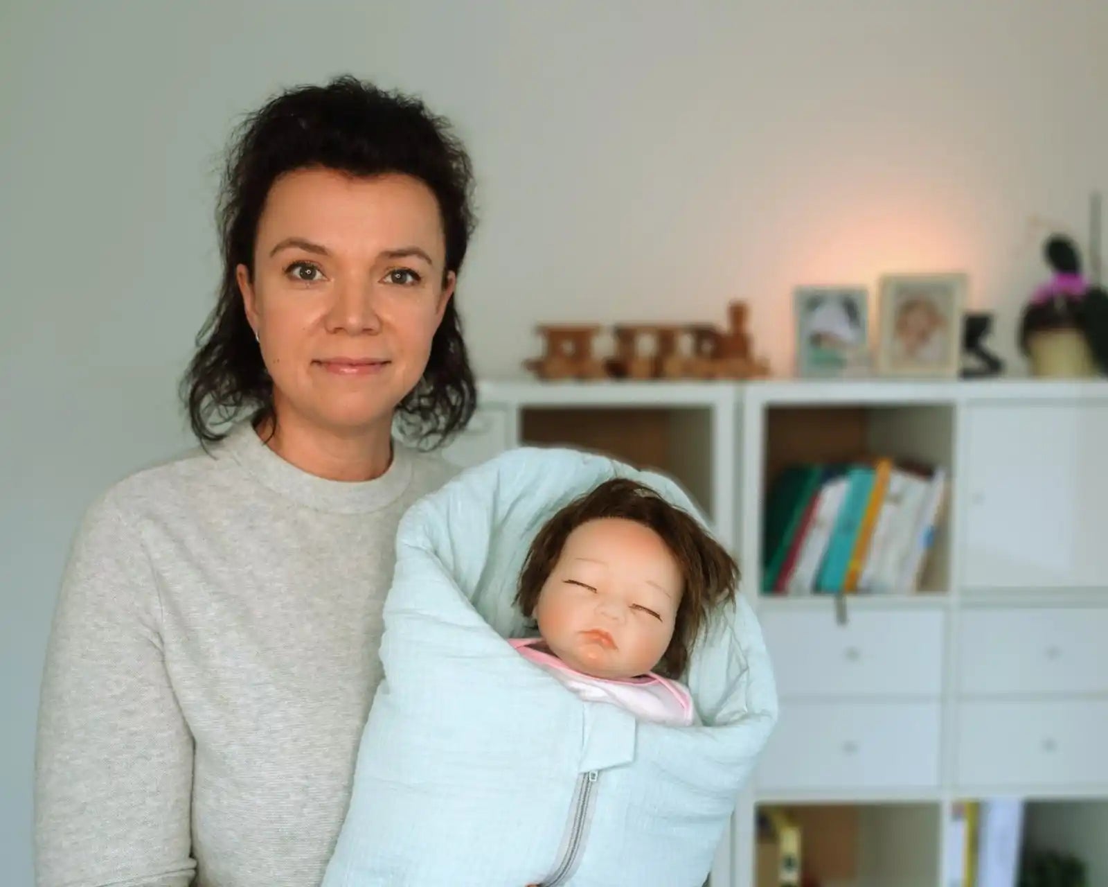 Frau, die eine Puppe hält, die in eine hellblaue Decke gewickelt ist