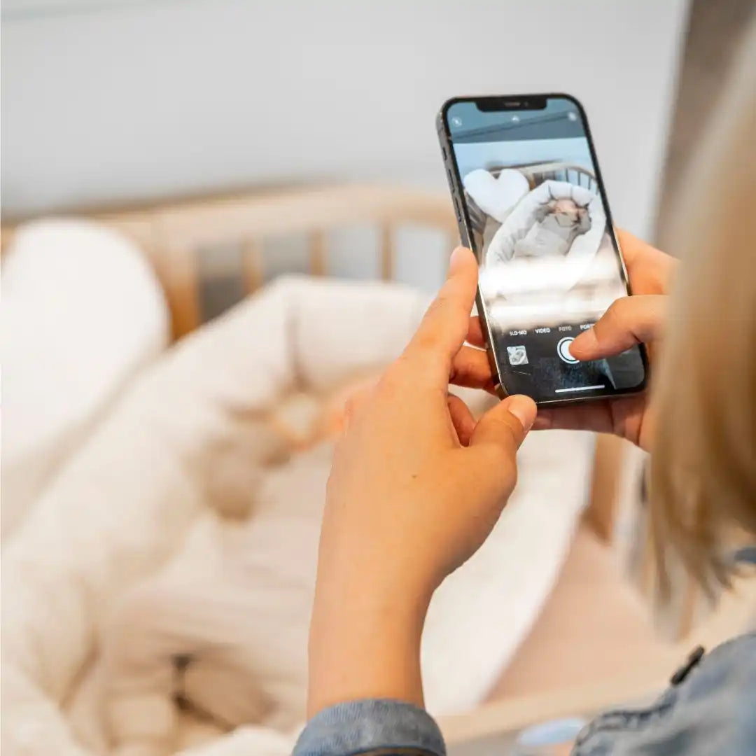 Eine Person hält ein Smartphone, um ein Baby zu fotografieren.